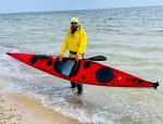 Гребець стоїть у воді та тримає туристичний каяк SeaBird XP 507